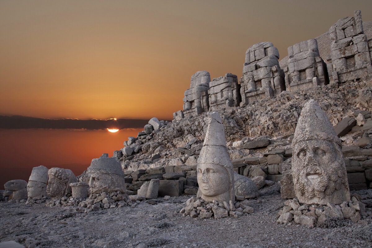 Image of ancient ruins with a sunset behind them.